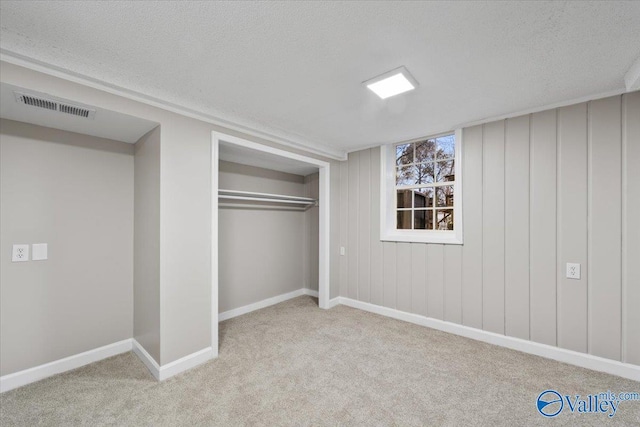 unfurnished bedroom featuring light colored carpet, a textured ceiling, and a closet