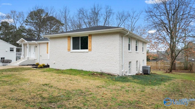 view of front of home with a front lawn and central AC