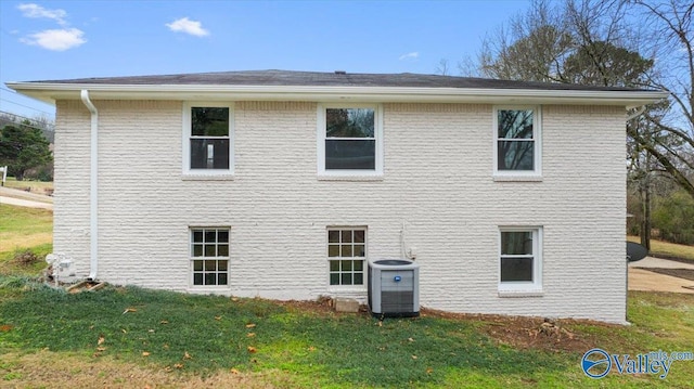 back of property featuring a lawn and central air condition unit