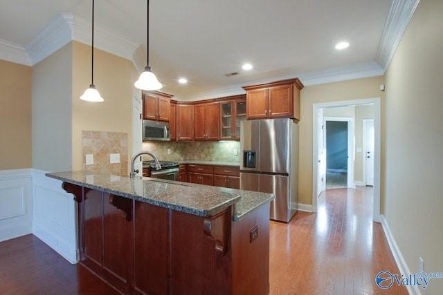 kitchen with pendant lighting, ornamental molding, tasteful backsplash, kitchen peninsula, and stainless steel appliances