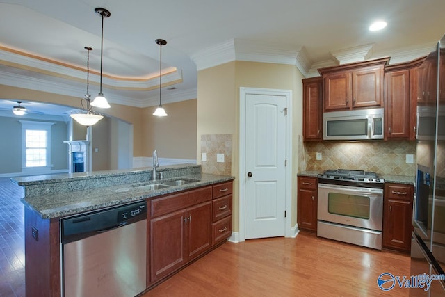 kitchen with sink, stainless steel appliances, tasteful backsplash, dark stone counters, and decorative light fixtures