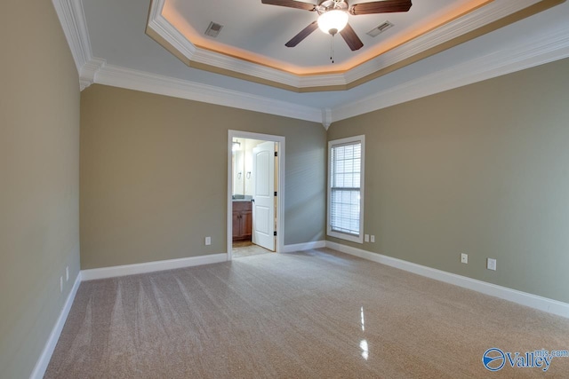 unfurnished bedroom with ceiling fan, crown molding, ensuite bathroom, a tray ceiling, and light carpet