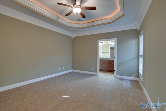 carpeted spare room featuring a tray ceiling, ceiling fan, plenty of natural light, and ornamental molding