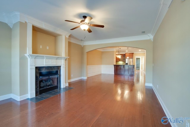 unfurnished living room with ceiling fan, dark hardwood / wood-style flooring, crown molding, and a tiled fireplace