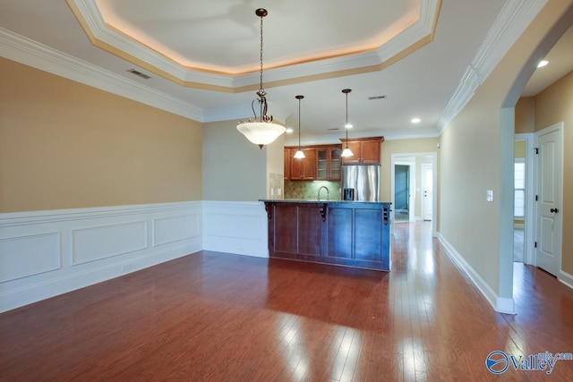 kitchen with kitchen peninsula, ornamental molding, a tray ceiling, pendant lighting, and stainless steel fridge with ice dispenser