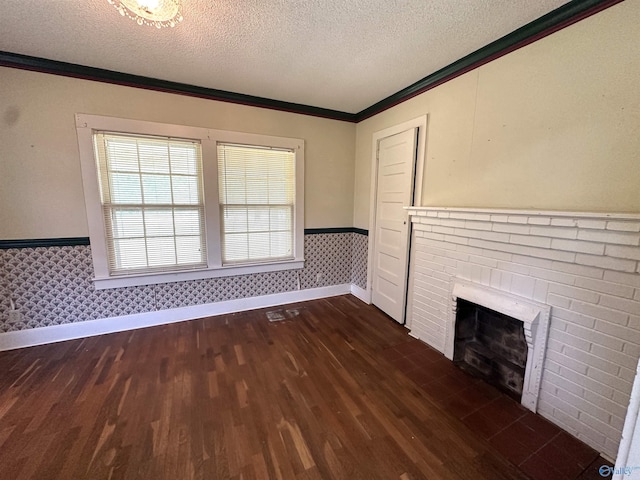 unfurnished living room featuring dark wood-type flooring, ornamental molding, a brick fireplace, and a textured ceiling