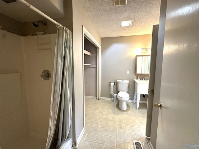 bathroom featuring vanity, toilet, a textured ceiling, and walk in shower