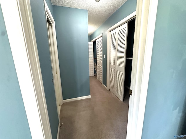 hallway with light carpet and a textured ceiling