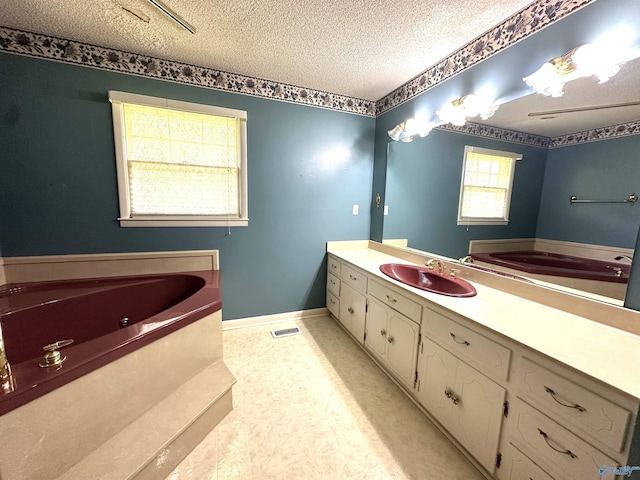 bathroom featuring vanity, a tub to relax in, and a textured ceiling