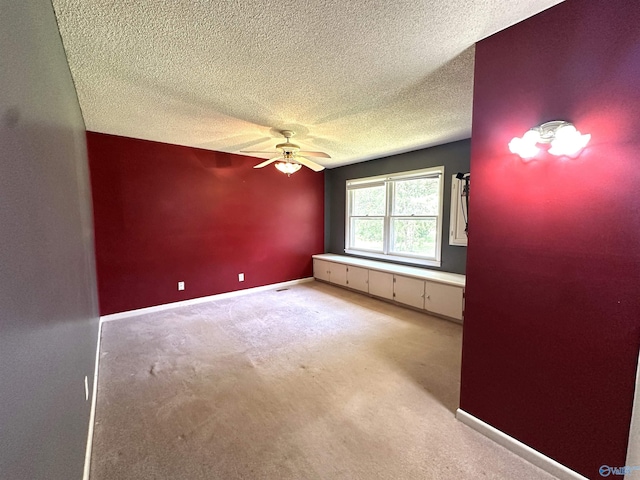 carpeted empty room with ceiling fan and a textured ceiling