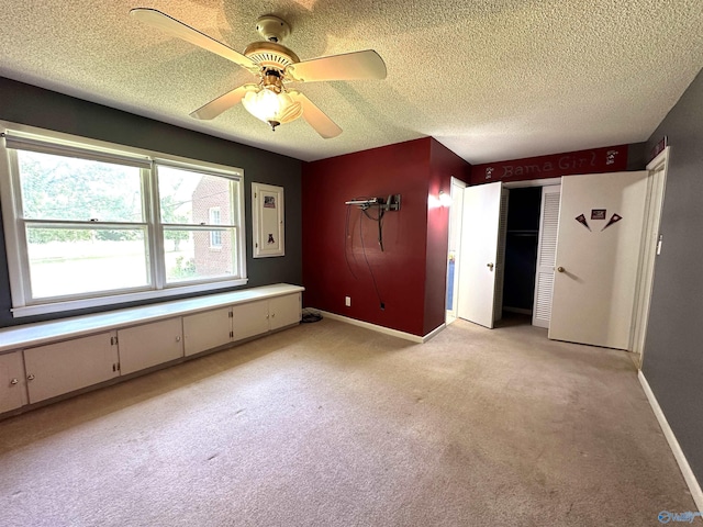 unfurnished bedroom with ceiling fan, light colored carpet, a closet, and a textured ceiling