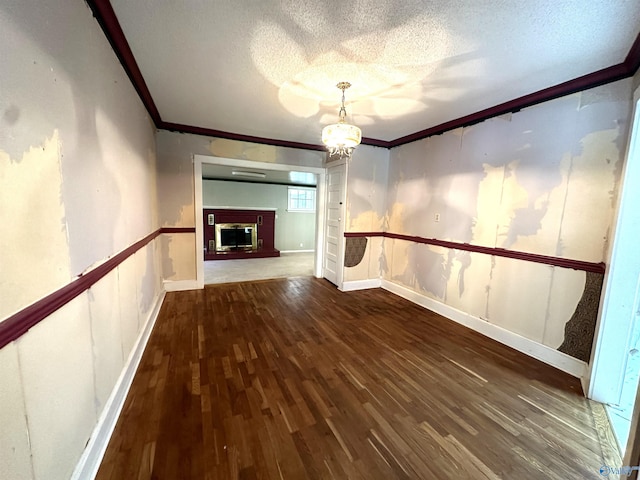 unfurnished living room featuring ornamental molding, dark hardwood / wood-style floors, a textured ceiling, and a notable chandelier