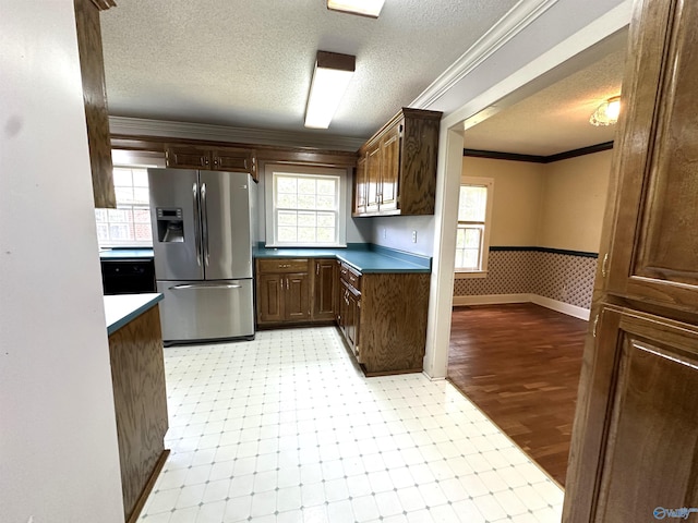 kitchen featuring crown molding, stainless steel fridge with ice dispenser, a textured ceiling, and light wood-type flooring