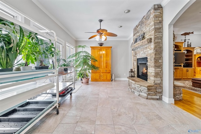 interior space featuring a fireplace, ceiling fan, light hardwood / wood-style floors, and crown molding