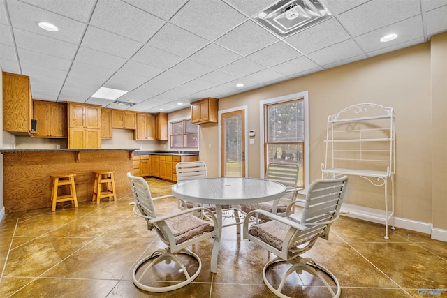 tiled dining space featuring a drop ceiling