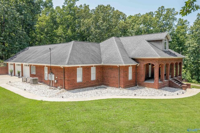 rear view of house with a lawn, central AC, and a garage