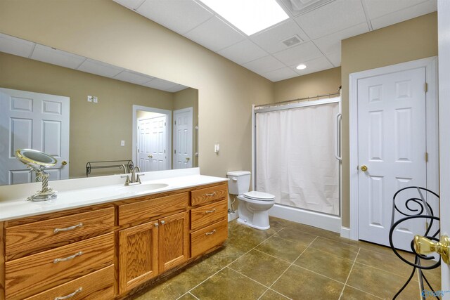 bathroom featuring vanity, tile patterned floors, a drop ceiling, a shower, and toilet