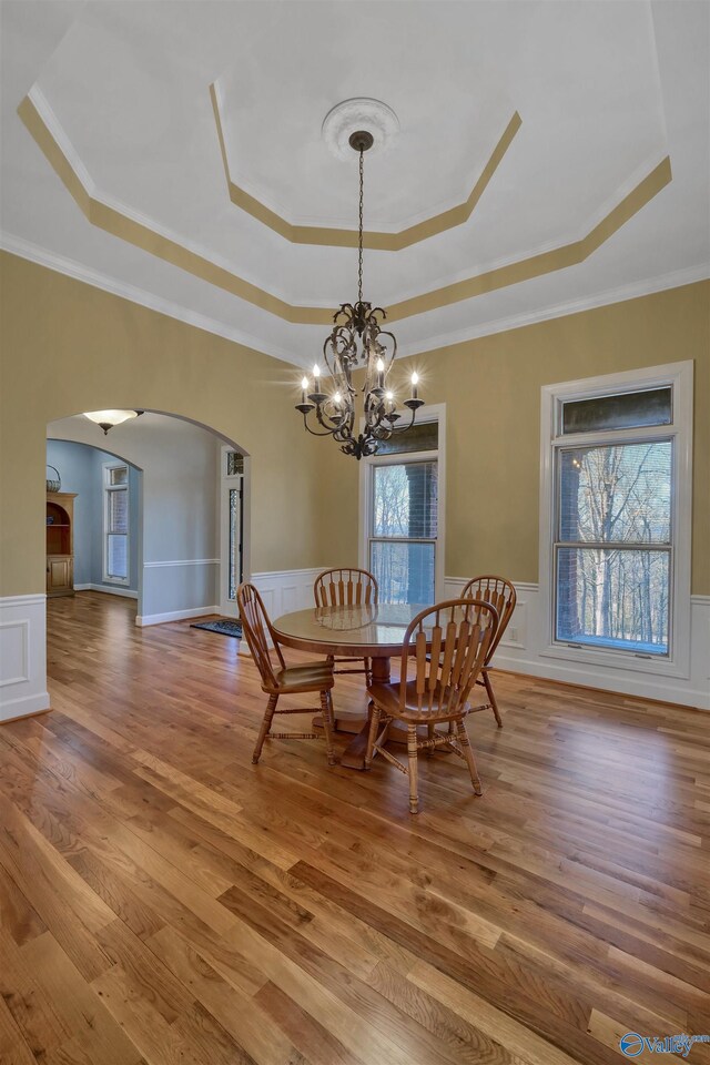 dining room with hardwood / wood-style floors, a raised ceiling, and a chandelier