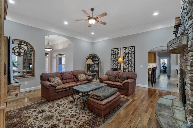 living room featuring ceiling fan, hardwood / wood-style floors, crown molding, and a fireplace