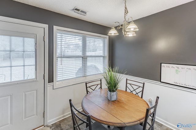 dining area featuring a textured ceiling, a wealth of natural light, and a notable chandelier