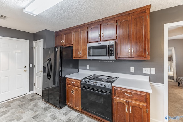 kitchen with a textured ceiling and black appliances