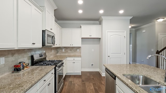 kitchen with dark wood-type flooring, a sink, appliances with stainless steel finishes, light stone countertops, and crown molding