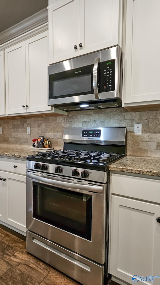 kitchen with appliances with stainless steel finishes, white cabinets, and tasteful backsplash