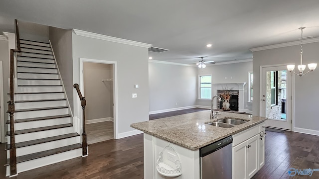 kitchen with visible vents, dark wood finished floors, a stone fireplace, stainless steel dishwasher, and a sink