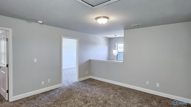 spare room with visible vents, baseboards, and dark colored carpet