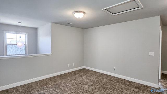 empty room featuring attic access, dark colored carpet, visible vents, and baseboards