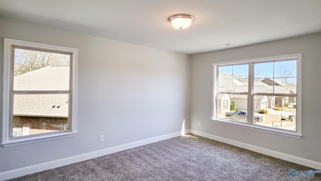 spare room featuring carpet, visible vents, and baseboards