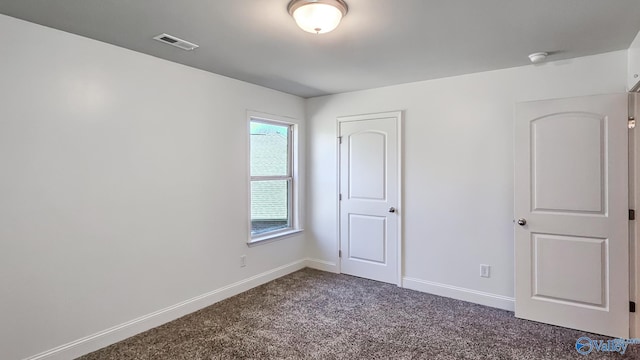 spare room featuring baseboards, visible vents, and carpet flooring