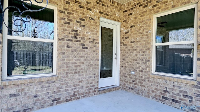 view of exterior entry featuring a patio area and brick siding