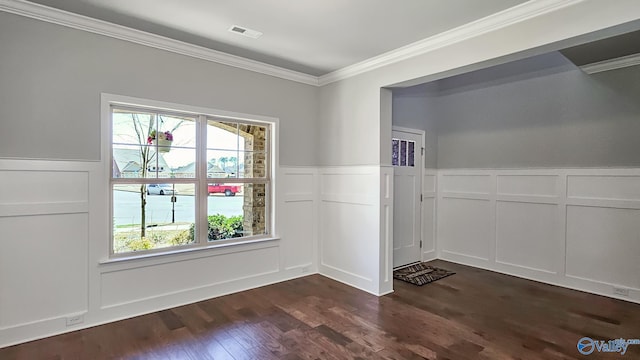 unfurnished dining area with dark wood-type flooring, visible vents, crown molding, and a decorative wall