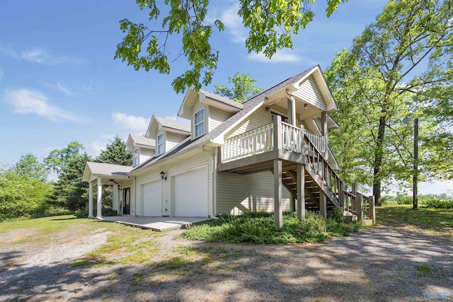 view of side of property with dirt driveway, stairs, an attached garage, and a deck