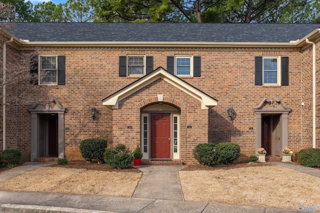 view of property with brick siding and roof with shingles