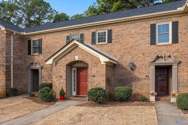 view of front of home featuring brick siding and a shingled roof