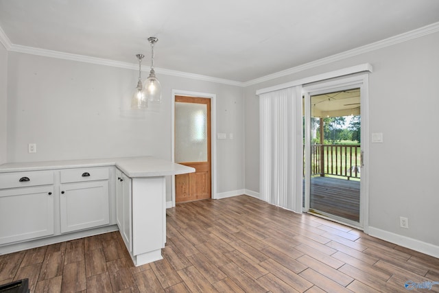 kitchen featuring hanging light fixtures, wood-type flooring, ornamental molding, white cabinetry, and kitchen peninsula