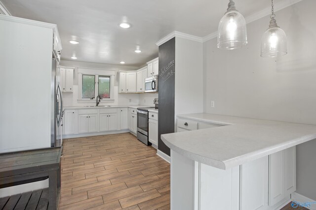 kitchen featuring appliances with stainless steel finishes, decorative light fixtures, sink, crown molding, and kitchen peninsula