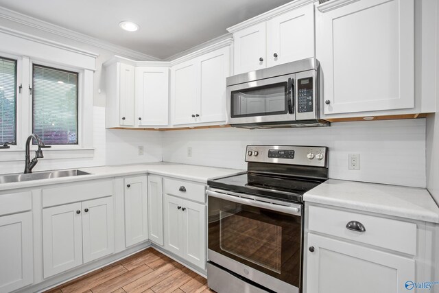 kitchen with sink, stainless steel appliances, white cabinets, and hardwood / wood-style flooring