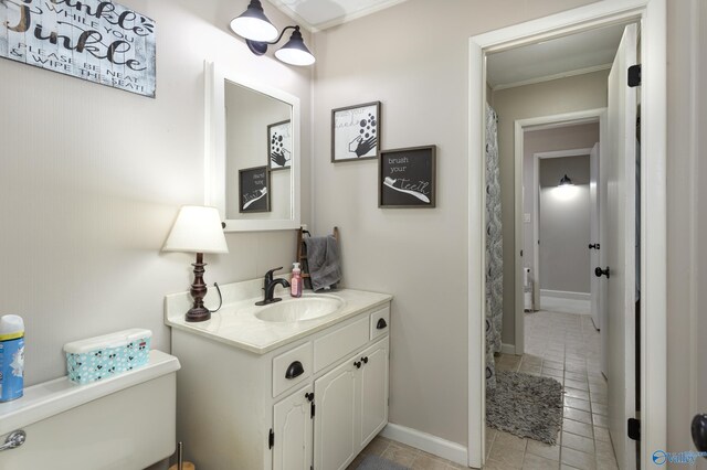 bathroom with tile patterned flooring, toilet, ornamental molding, and vanity