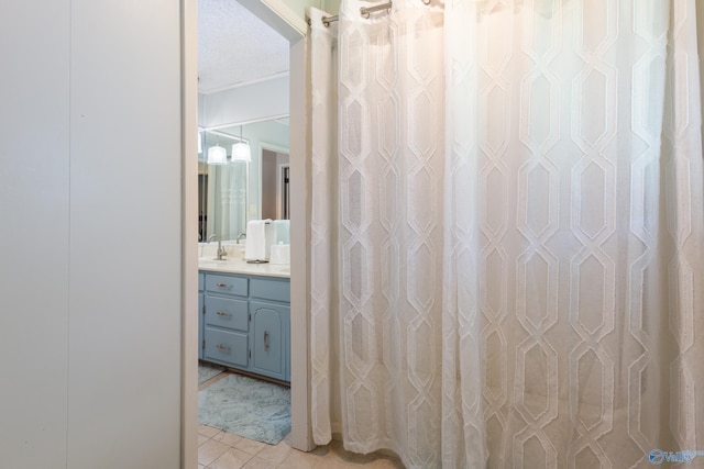 bathroom with a textured ceiling, vanity, and tile patterned flooring