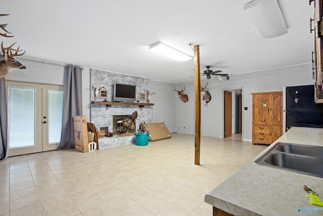 kitchen with french doors, ceiling fan, a fireplace, sink, and fridge