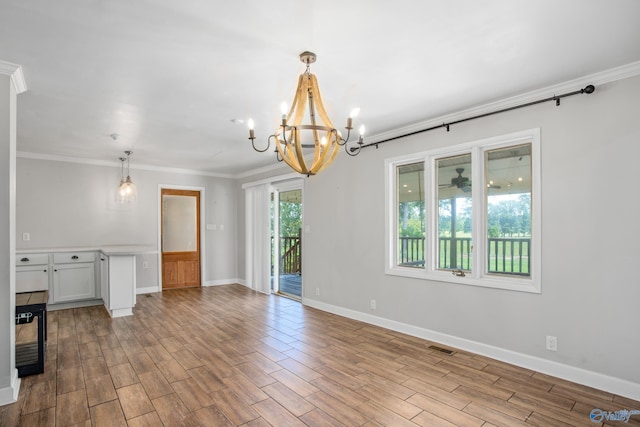 empty room with hardwood / wood-style floors, an inviting chandelier, and crown molding