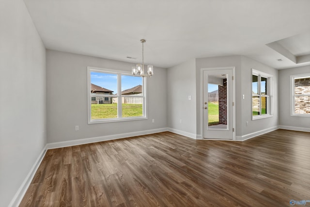 unfurnished dining area with dark wood-type flooring and an inviting chandelier