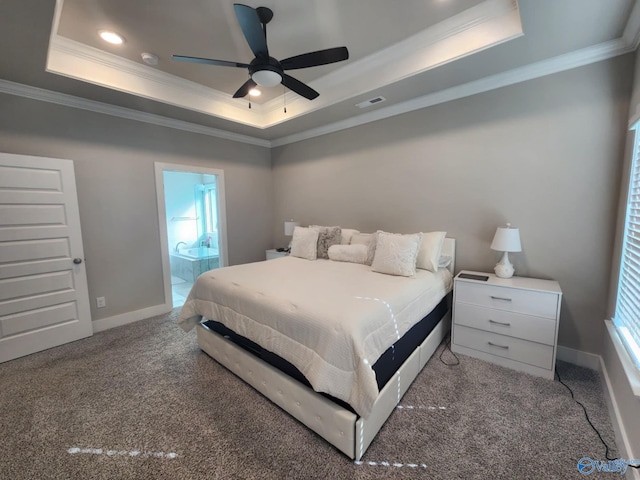 bedroom with a tray ceiling, ceiling fan, dark carpet, connected bathroom, and crown molding