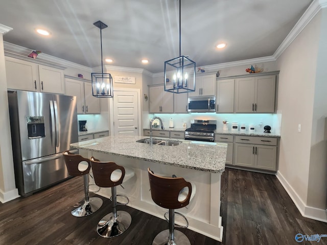 kitchen with dark hardwood / wood-style floors, hanging light fixtures, stainless steel appliances, sink, and light stone counters