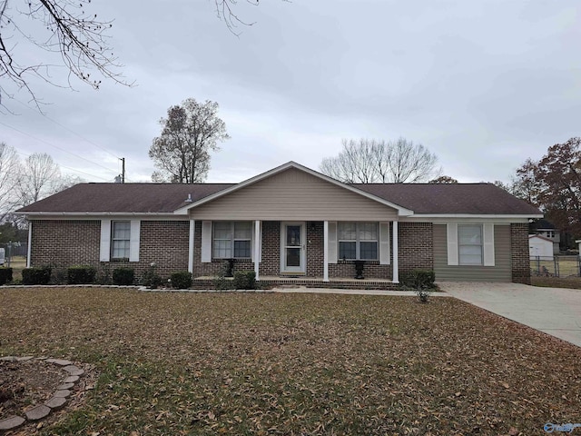 ranch-style home featuring brick siding, a front yard, and fence