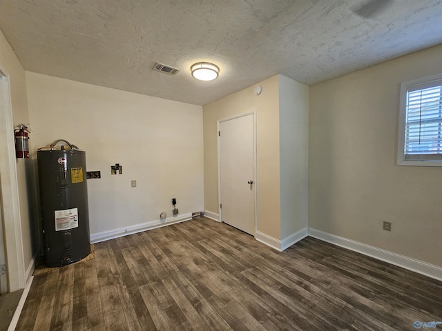 clothes washing area with water heater, dark hardwood / wood-style floors, and a textured ceiling