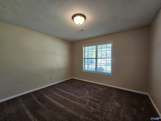 unfurnished room featuring a textured ceiling and dark colored carpet